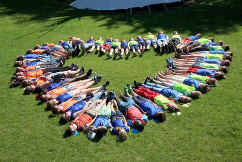 Viele Kinder bilden beim Waldpiratencamp gemeinsam ein großes Herz auf der Wiese
